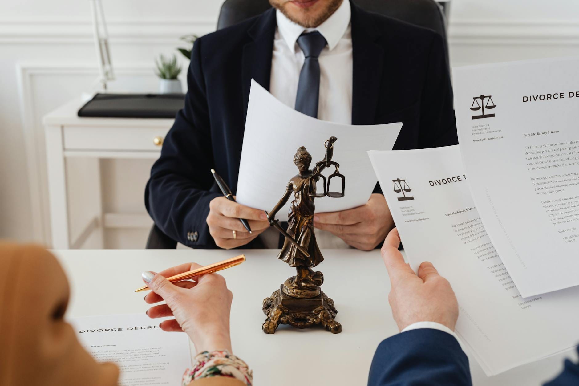 Prawnicy analizują dokumenty rozwodowe w kancelarii obok statuety Temidy
